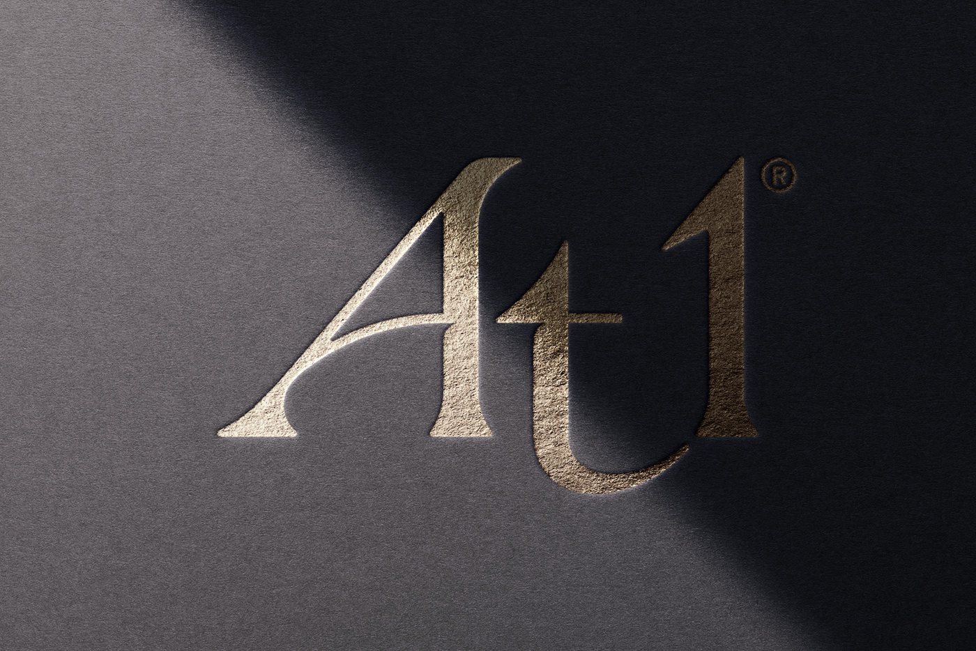 At1 logo in gold foil on a black background