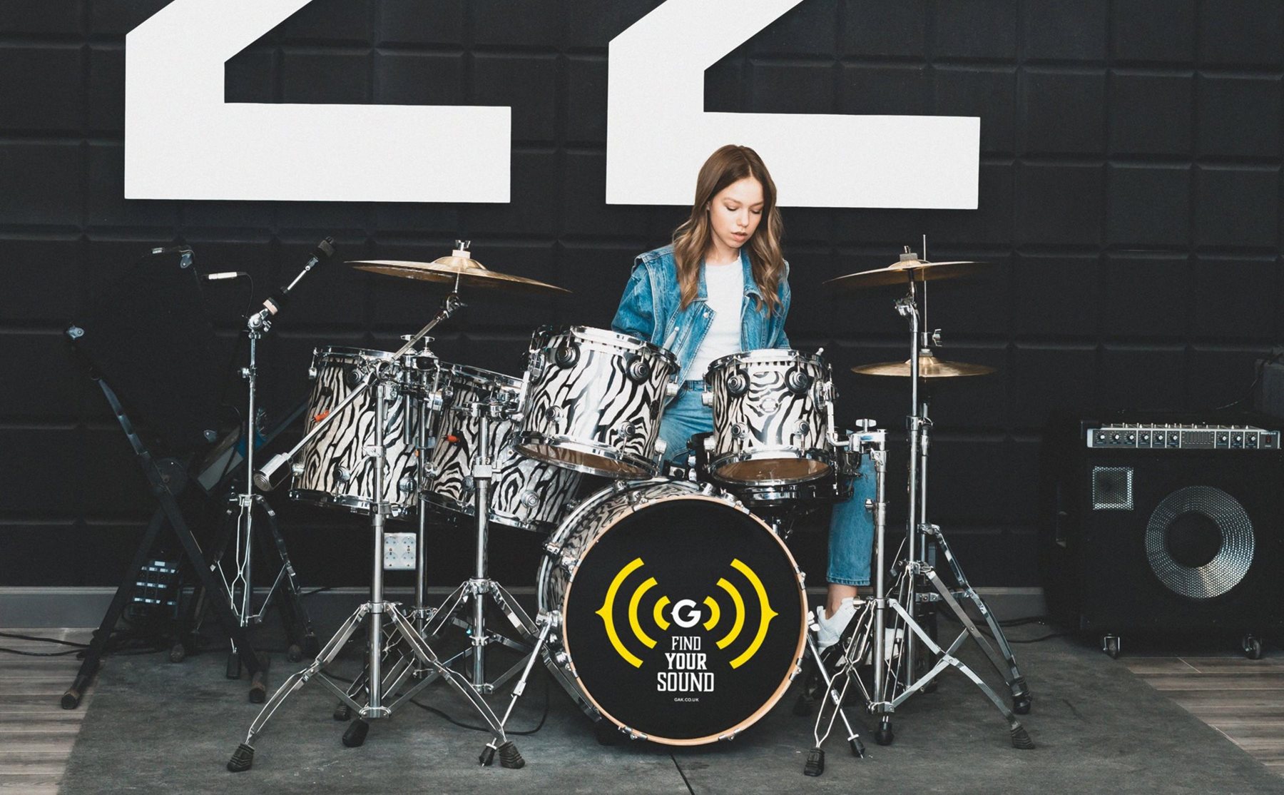 Young woman on drum emblazoned with GAK logo