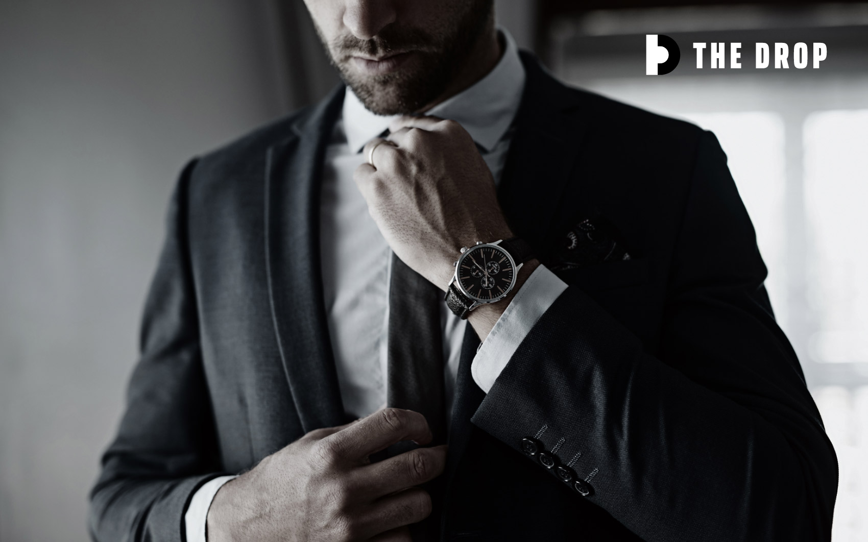 Man in suit adjusting tie with logo