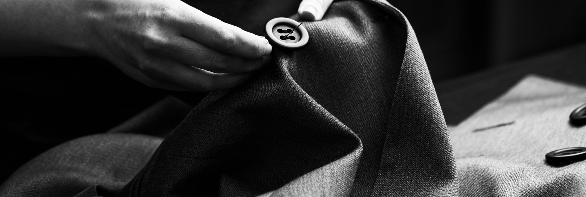 Close-up of hand carefully sowing a button on to a jacket