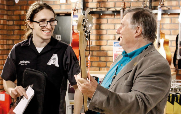 Staff member with customer holding guitar