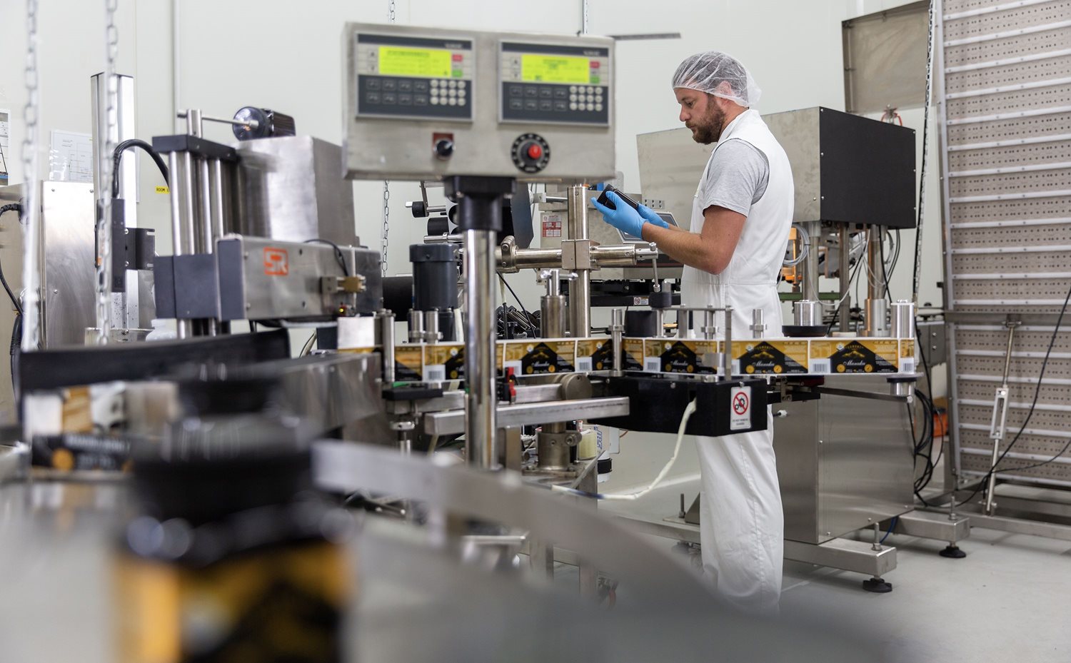 A shot of a bearded man in a lab with hair net preparing some tools used for testing the honey