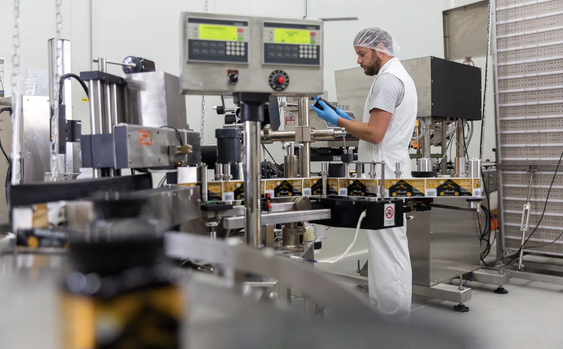A shot of a bearded man in a lab with hair net preparing some tools used for testing the honey